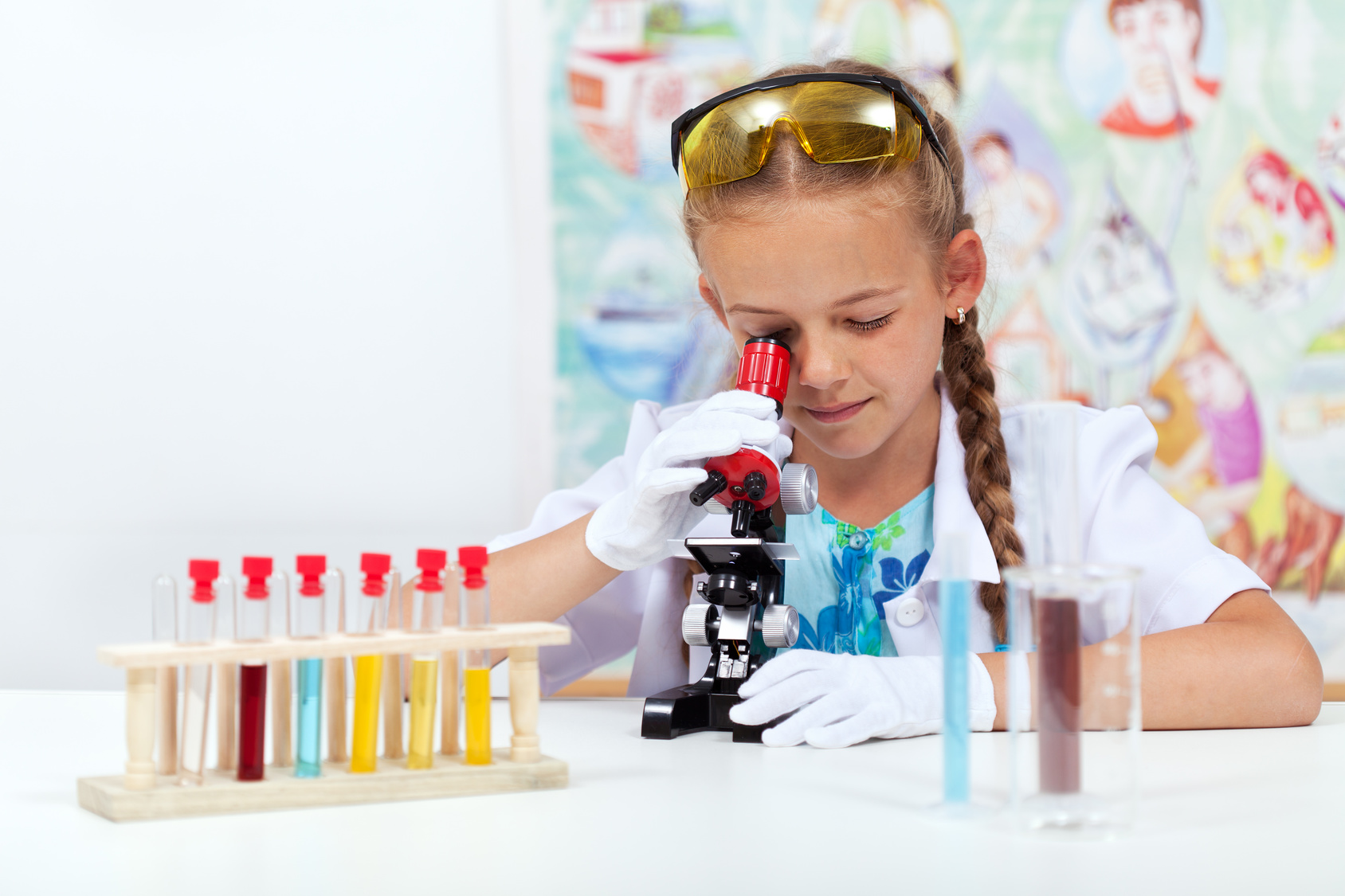 Little girl in elementary school science class using microscope